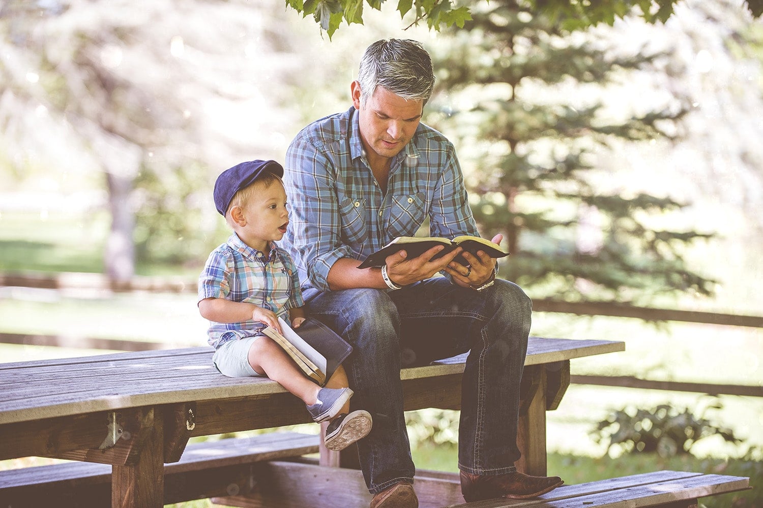 A closeup shot of a male reading the bible for his child with a blurred background